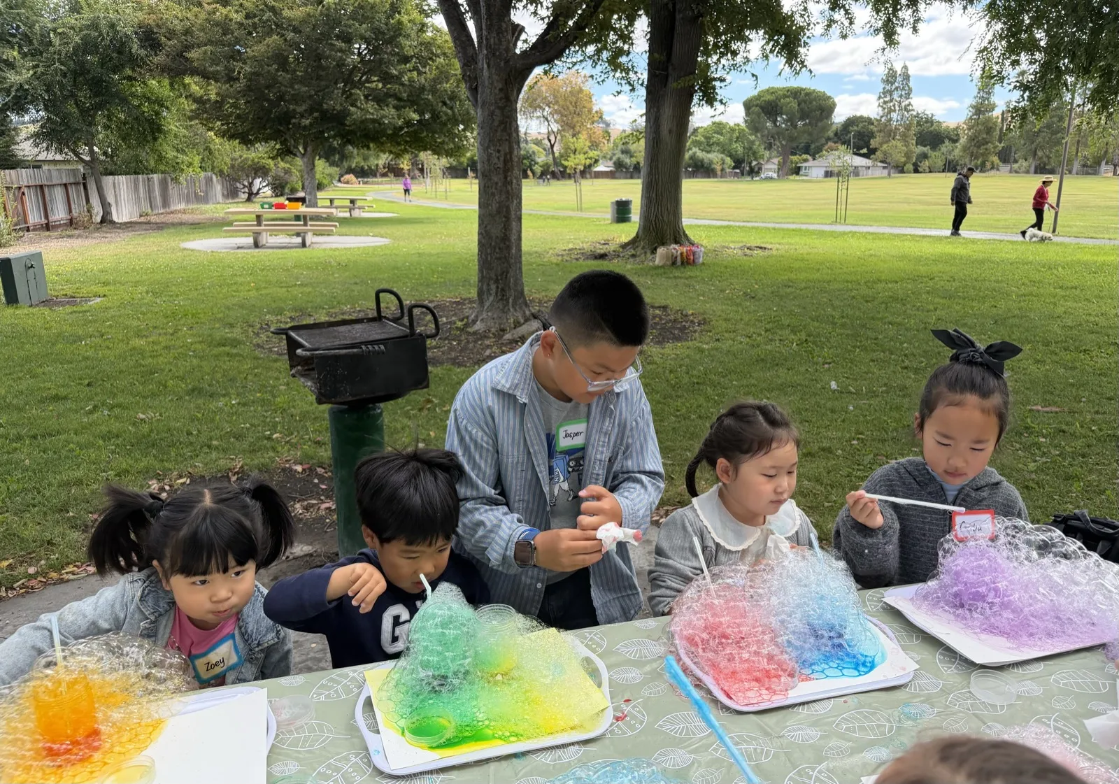 Children creating colorful bubble art during an outdoor Curious Bloom Lab activity