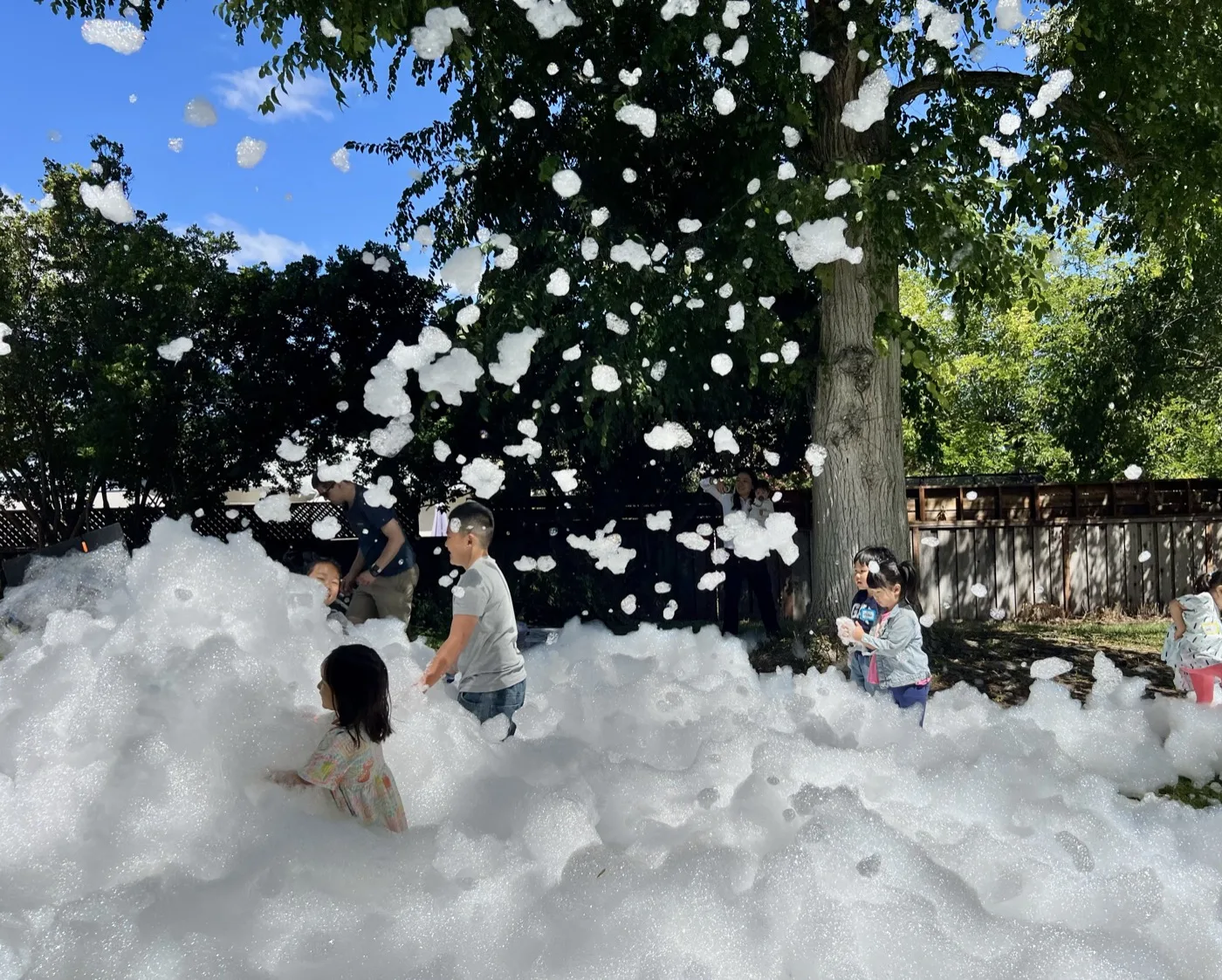 Children playing in foam during a Curious Bloom Lab outdoor event