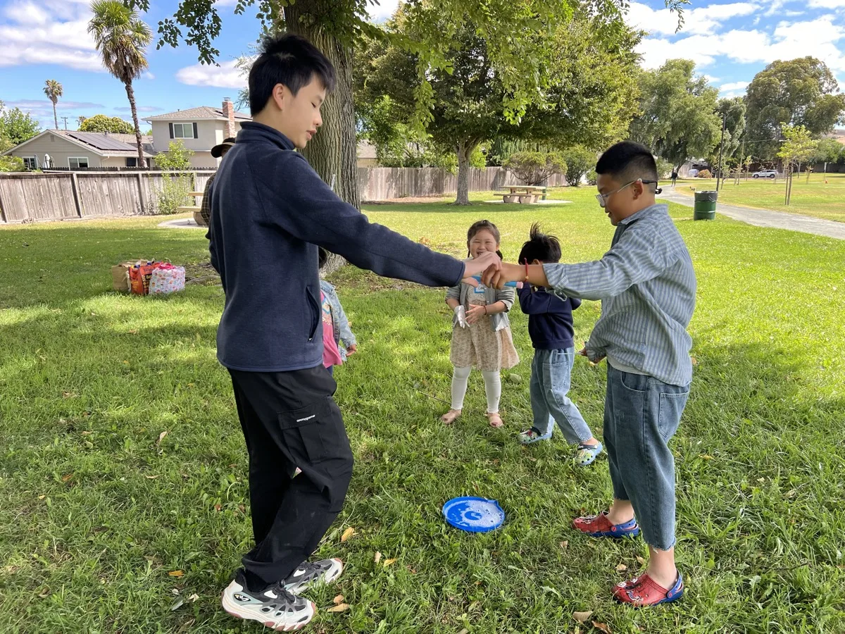 Older children helping younger children during a Curious Bloom Lab activity